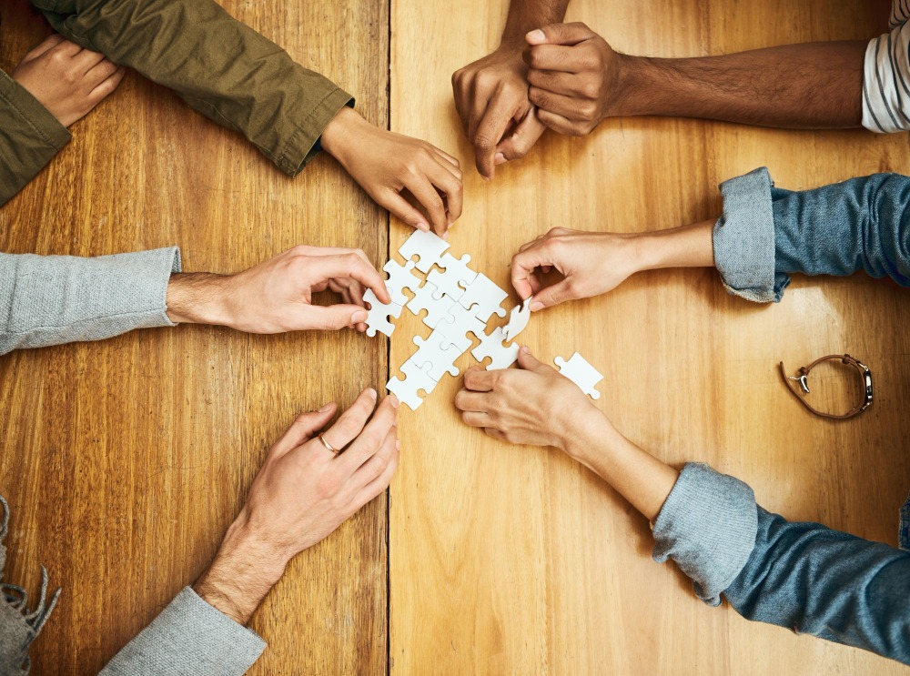 Multiple people holding jigsaw puzzle pieces showing workforce engagement